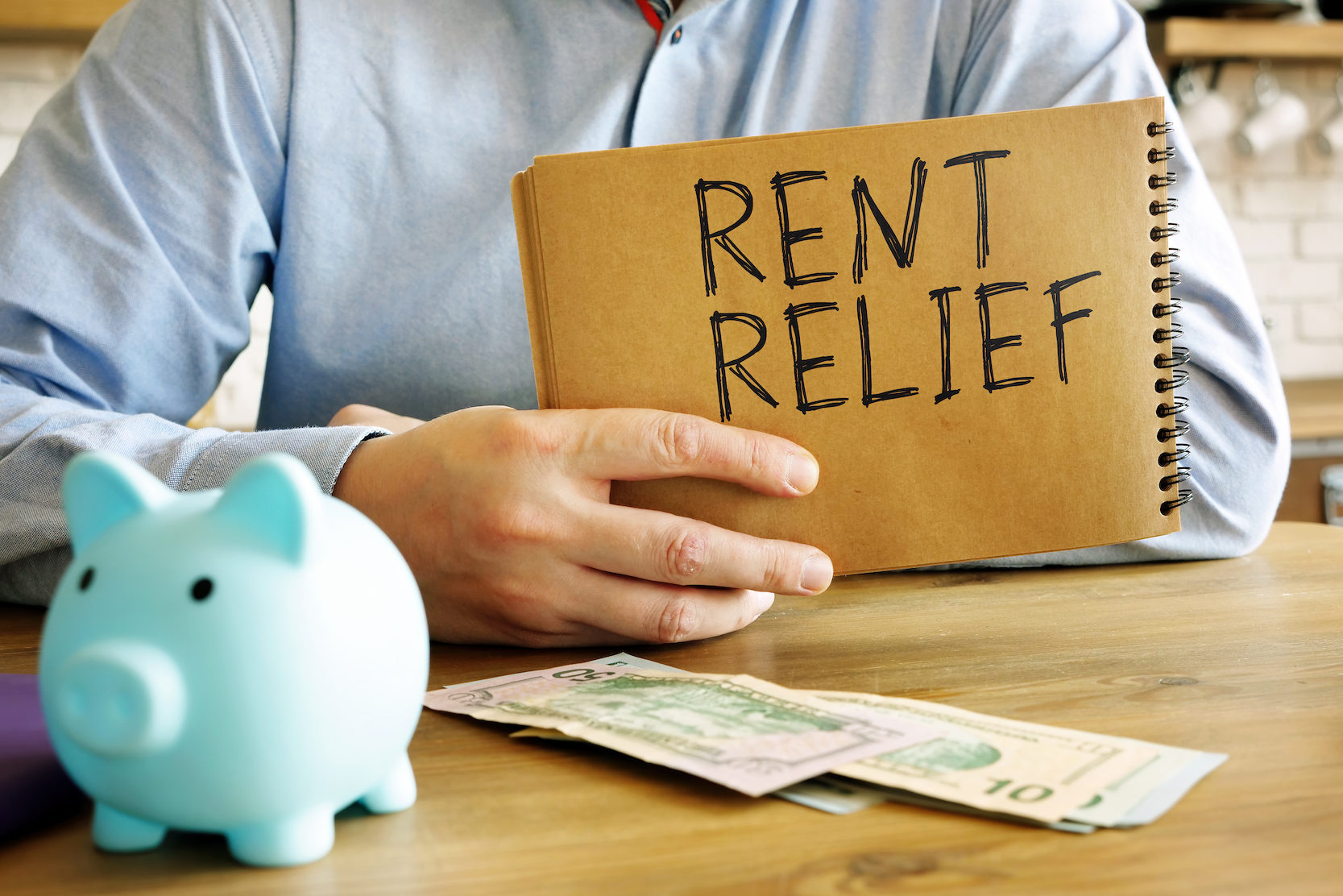 Rent relief. A man at home holds a handwritten lettering.